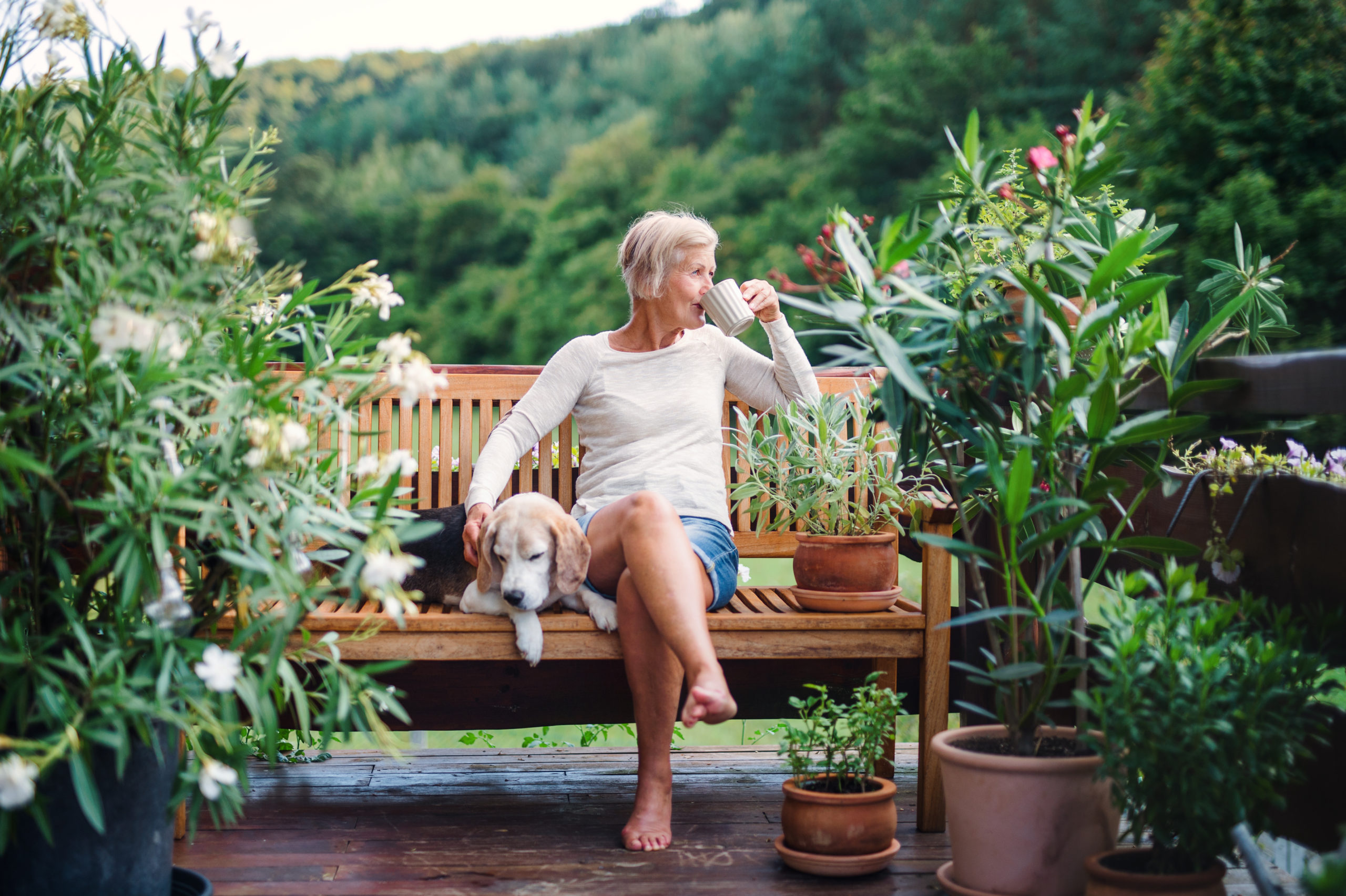 Eine ältere Dame sitzt im Garten auf der Terrasse