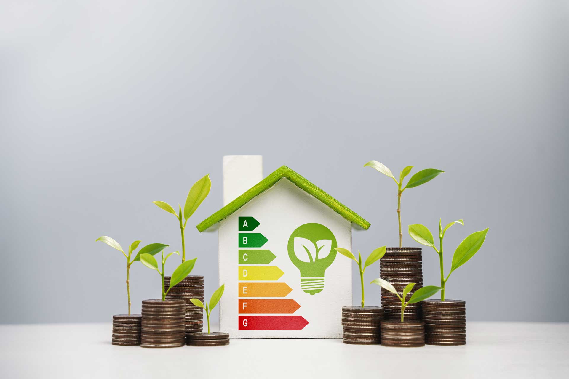 Modellhaus mit Energieeffizienzskala und Münzen, Wert von Immobilien
