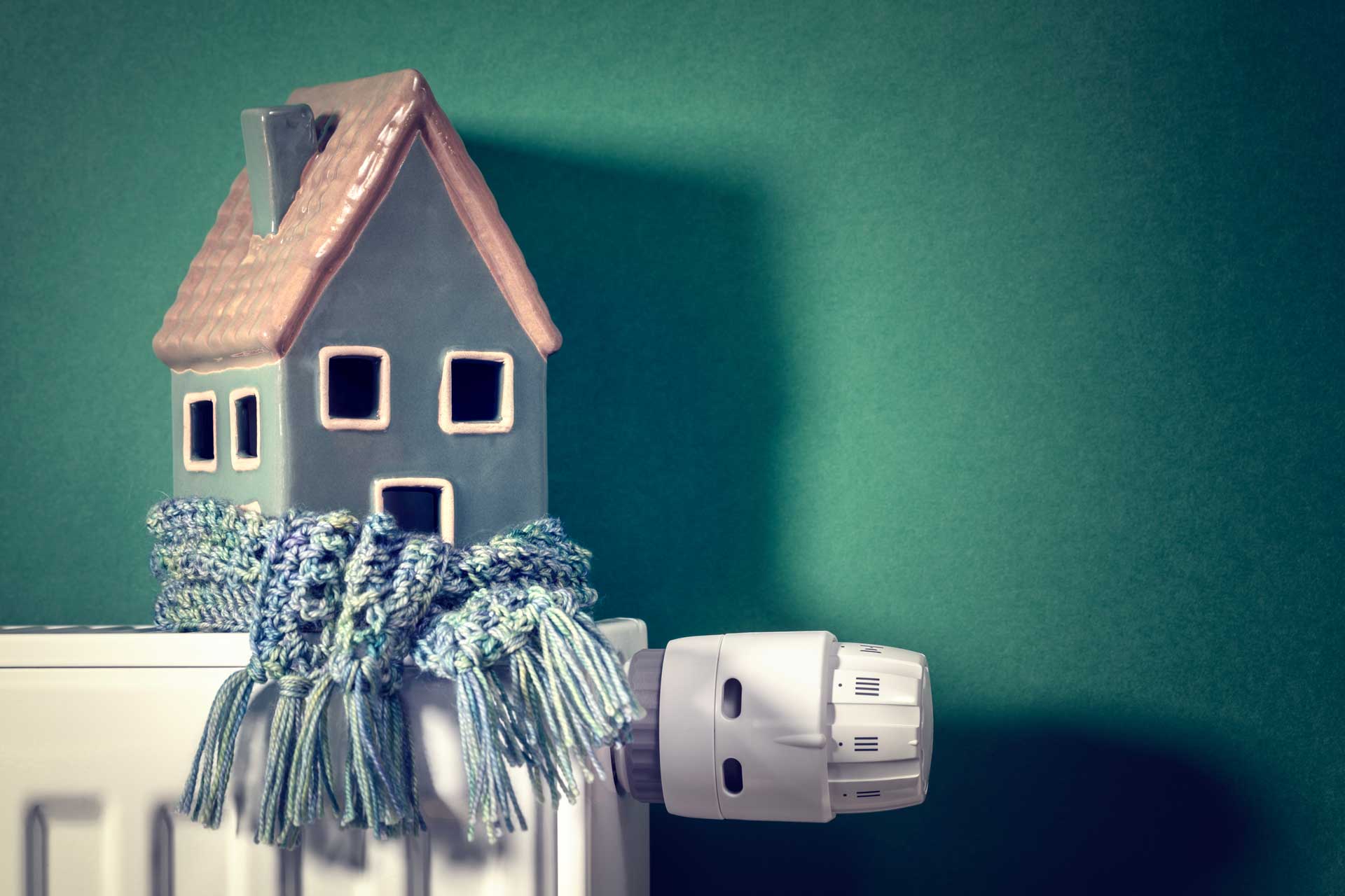 Modellhaus auf Heizung mit Schal, Haus im Winter schützen