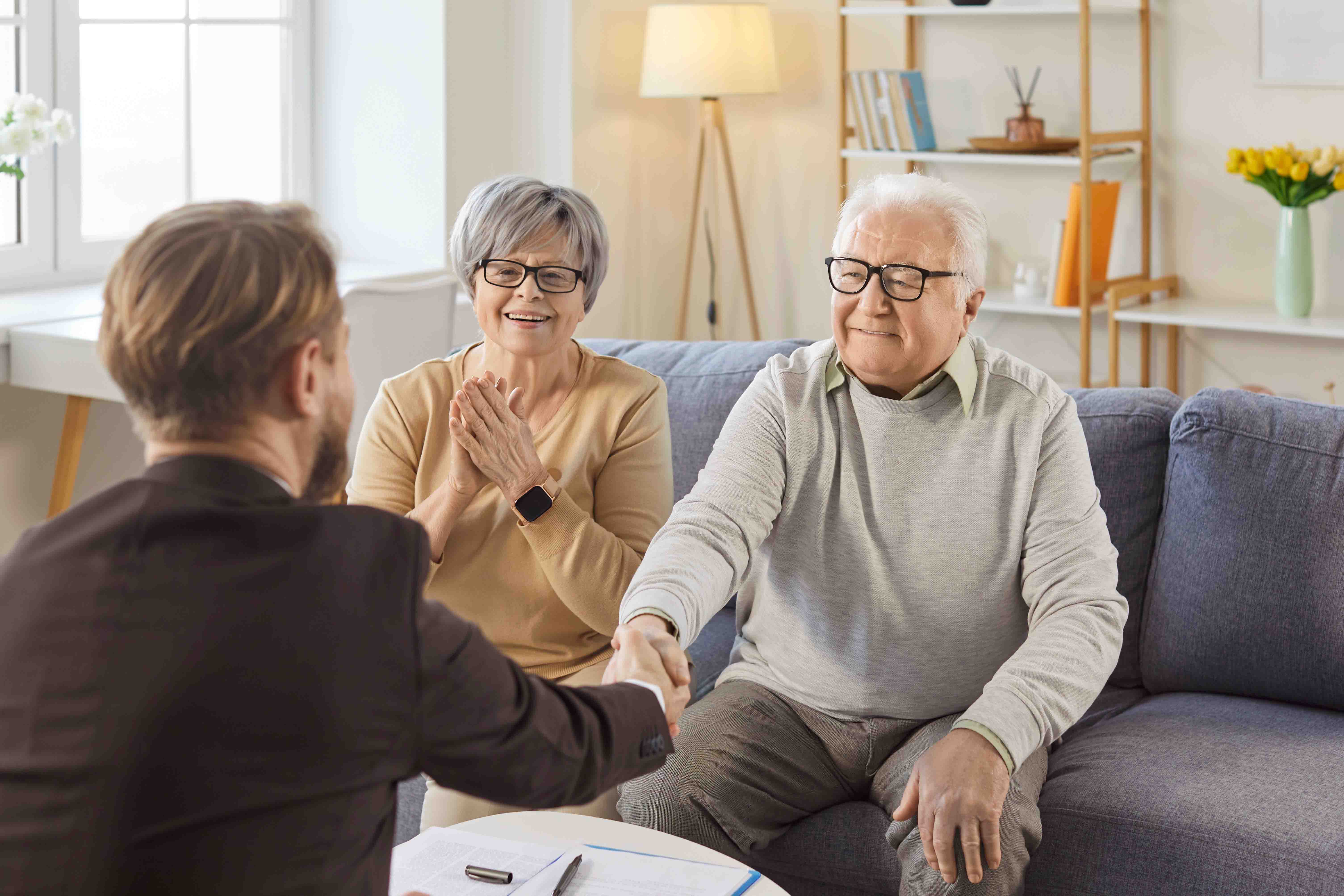 Handschlag zwischen Makler und Seniorenpaar